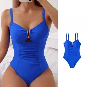 Detail of royal blue one-piece swimsuit with V-shaped metal buckle and ruched fabric texture