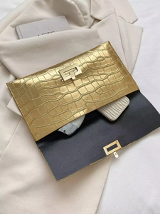 Detail of gold crocodile embossed clutch bag showing internal storage for phone and mirror