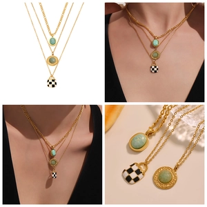 Detail of layered gold necklaces with green stone pendants and checkered square charm