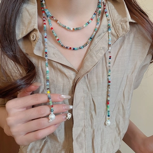Detail of bohemian colorful crystal beads with large white pearls on a linen shirt