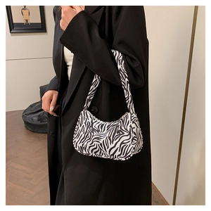Sac sous le bras à imprimé zébré noir et blanc porté avec un blazer noir chic