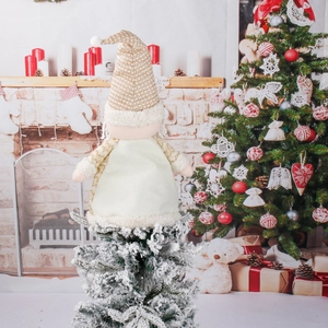 Sparkly gold gnome Christmas tree topper on snow-dusted branches in cozy room