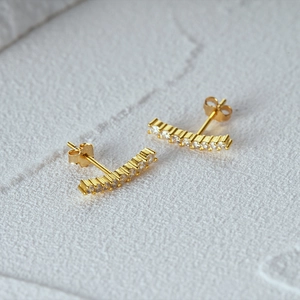 Macro shot of minimalist gold S925 sterling silver curved earrings with sparkling crystals
