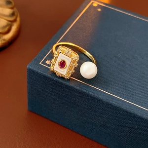Macro shot of gold plated ring with ruby enamel center and white pearl detail