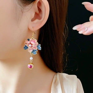 Detail of vintage floral earrings with pink enamel, pearls, and gold tassels on model