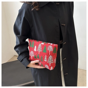 Detail einer roten Weihnachts-Kosmetiktasche mit Tannenbaum-Motiv, gehalten von einem Model