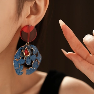 Detail of vintage flower leaf earring with red round pendant and blue enamel floral motifs