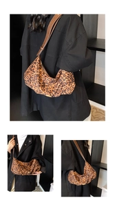 Detailed close-up of leopard print crescent bag with brown strap and gold zipper details