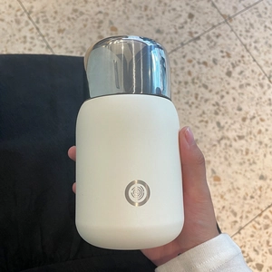 Close-up of white stainless steel vacuum flask with silver metallic lid and minimal logo