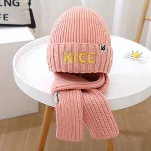 Detail of pink knitted winter set featuring NICE embroidery on beanie and matching scarf