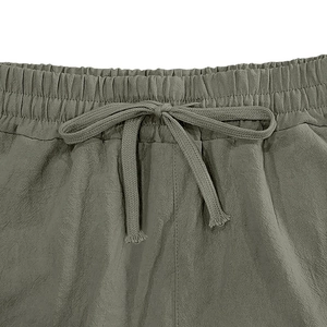 Detail of elastic waistband and braided drawstring on olive green linen blend shorts