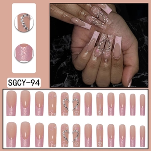 Long coffin press-on nails featuring pink glitter French tips and rhinestone hearts