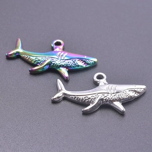 Macro shot of shark-shaped stainless steel charms in silver and rainbow iridescent finish
