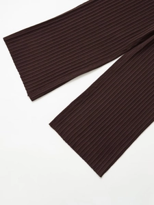 Dettaglio macro dei pantaloni in maglia caffè scuro con trama a coste verticali sull'orlo