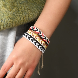 Close-up of four handmade braided rope bracelets in various colors worn on a wrist