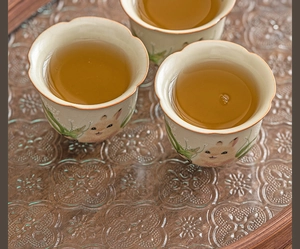Top view of three Ru kiln ceramic rabbit tea cups with flower petal rims on a wooden tray