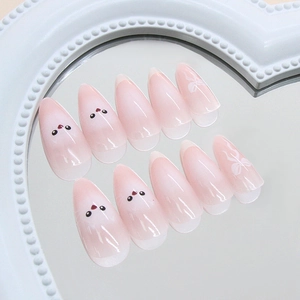Faux ongles French rose dégradé avec motifs de dessins animés et nœuds blancs