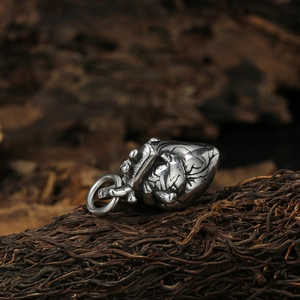 Retro anatomical heart pendant in polished silver steel on a rustic dark wood background