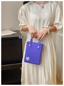 Detail einer lila EVA-Handtasche mit Deko-Knöpfen und einer blauen Blumenverzierung