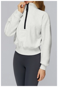 Detail of white half-zip cropped sweatshirt with black zipper and ribbed hem