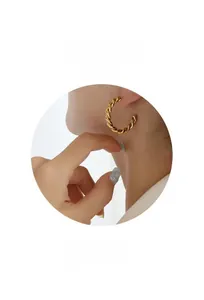 Gros plan de boucles d'oreilles créoles dorées en forme de C avec texture torsadée