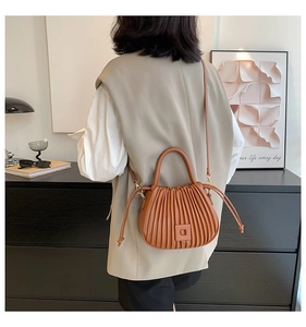 Detail of brown pleated handbag with square buckle and round handle for daily styling