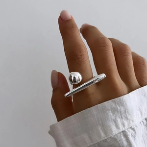 Detail of silver geometric open ring with sphere and bar design on model's finger