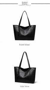 Detail of black tote bag featuring embossed skull patterns and leather tassels