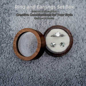 Detail of round walnut wood ring box with clear lid window and cream velvet interior