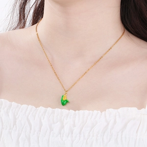 Detail of creative corn pendant necklace in gold and green enamel on model