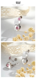 Macro detail of silver heart earrings with pink zircon stones and butterfly backings