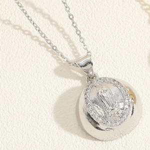 Macro view of silver necklace pendant featuring a Virgin Mary relief and white zircons