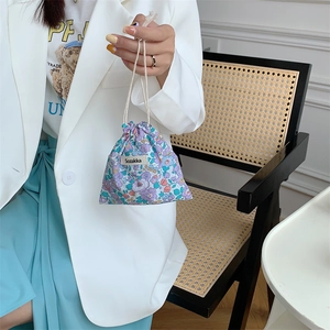 Handheld view of a floral cotton drawstring storage bag in light purple and blue tones