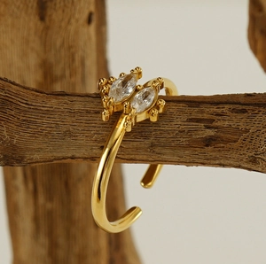 Detailed close-up of a gold-toned open ring with two marquise crystals on a wood stand
