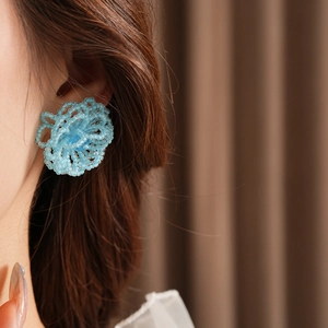 Close-up of blue beaded woven flower earrings on model with high quality details