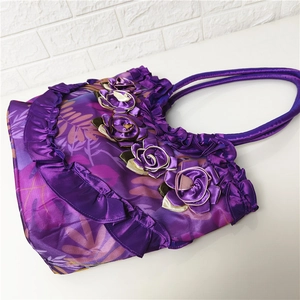 Detail of purple silk shoulder bag featuring 3D floral accents and ruffled texture