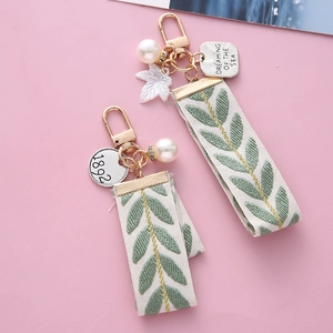 Detailed shot of striped ribbon keychain with pearl charm and engraved metal tags