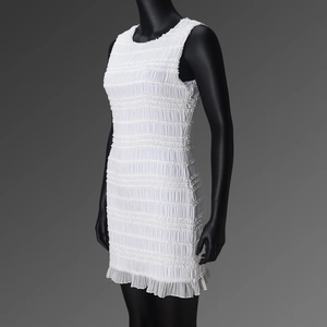 Détail d'une robe blanche sans manches plissée avec tissu texturé et ourlet à volants