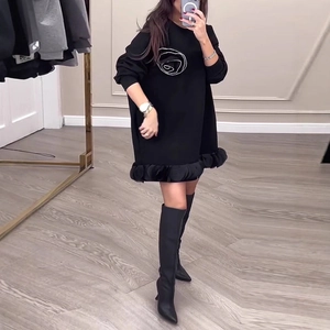 Détail d'une robe sweat noire avec imprimé rose blanche et ourlet à volants