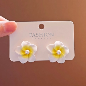Close-up of white plumeria flower stud earrings with yellow gradient and pearl center