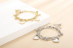 Detail of double-layered heart charm bracelets in gold and silver finish on a pedestal