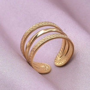 Detailed close-up of a triple-layered gold stainless steel ring with woven texture details
