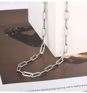 Detailed close-up of a silver paperclip chain necklace on a minimalist prop