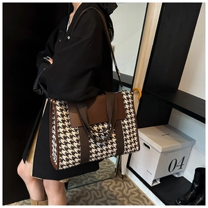 Detail of vintage houndstooth tote bag with brown leather trim worn by a model
