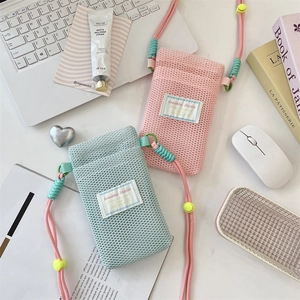 Detail of blue and pink mesh phone bags with adjustable ropes on a white desk