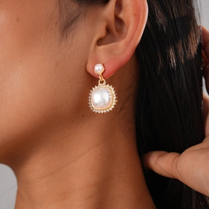 Detail of vintage gold pearl earrings with sparkling rhinestones on a female model's ear