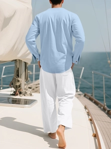 Herren Set aus hellblauem Leinenhemd und weißer Hose auf einem sonnigen Yachtdeck