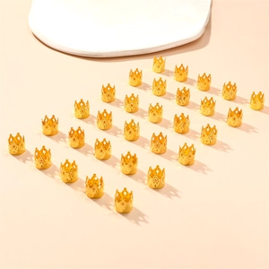 Detailed grid of twenty-four golden crown charms for ethnic braids on pink background