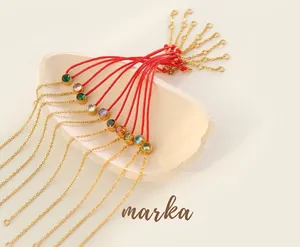 Close-up of red woven rope bracelets with gold chains and colorful round zircon stones