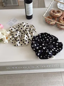 Detailed view of oversized satin polka dot scrunchies with elegant pearl embellishments